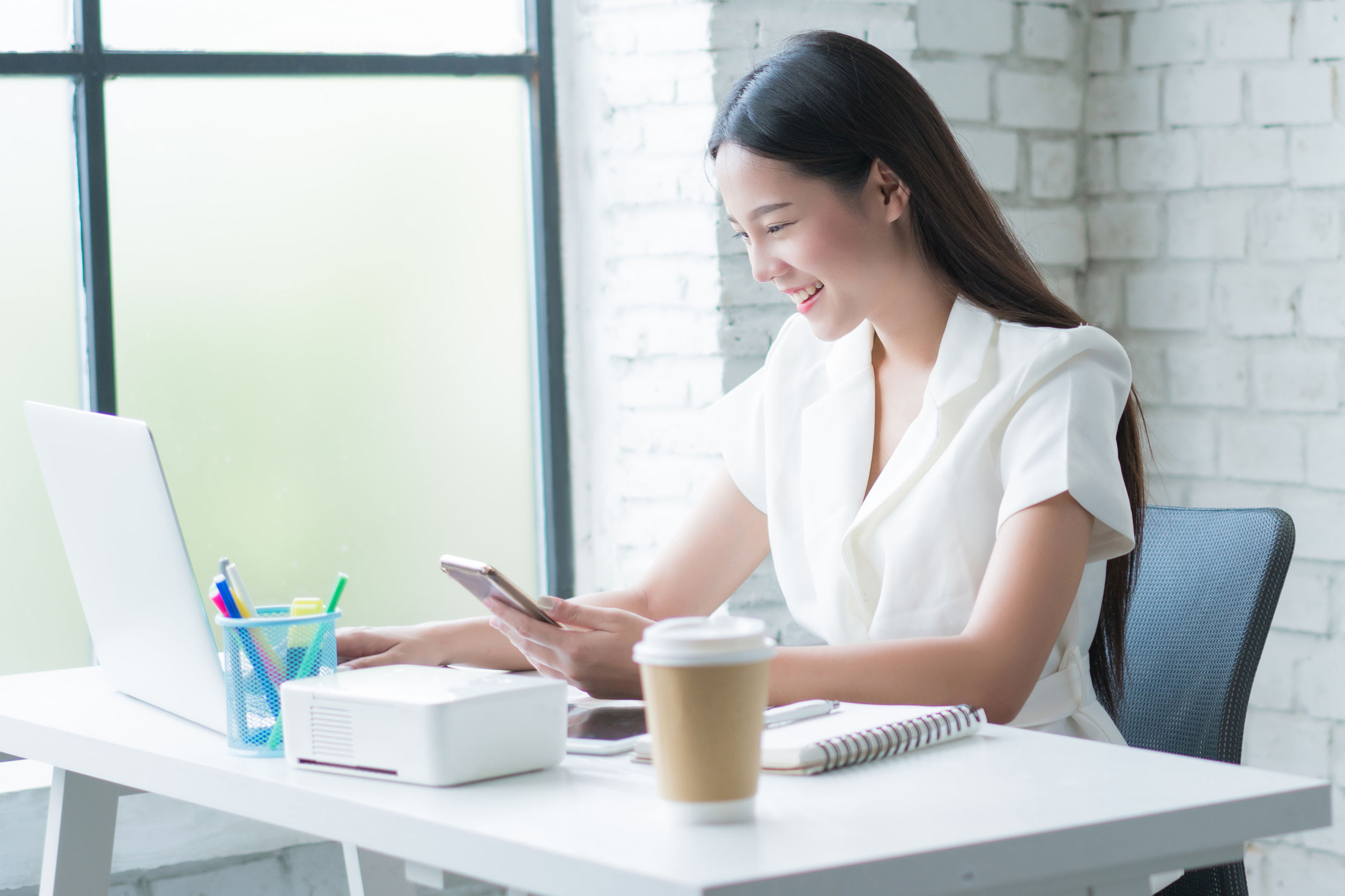 Mujere asiática trabajan ahora en el escritorio de su casa es feliz.